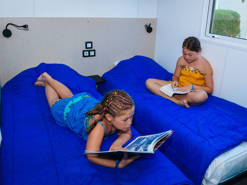 enfant en train de lire dans la chambre d'un mobil-home camping Chadotel La Trévillière à Brétignolles sur Mer en Vendée